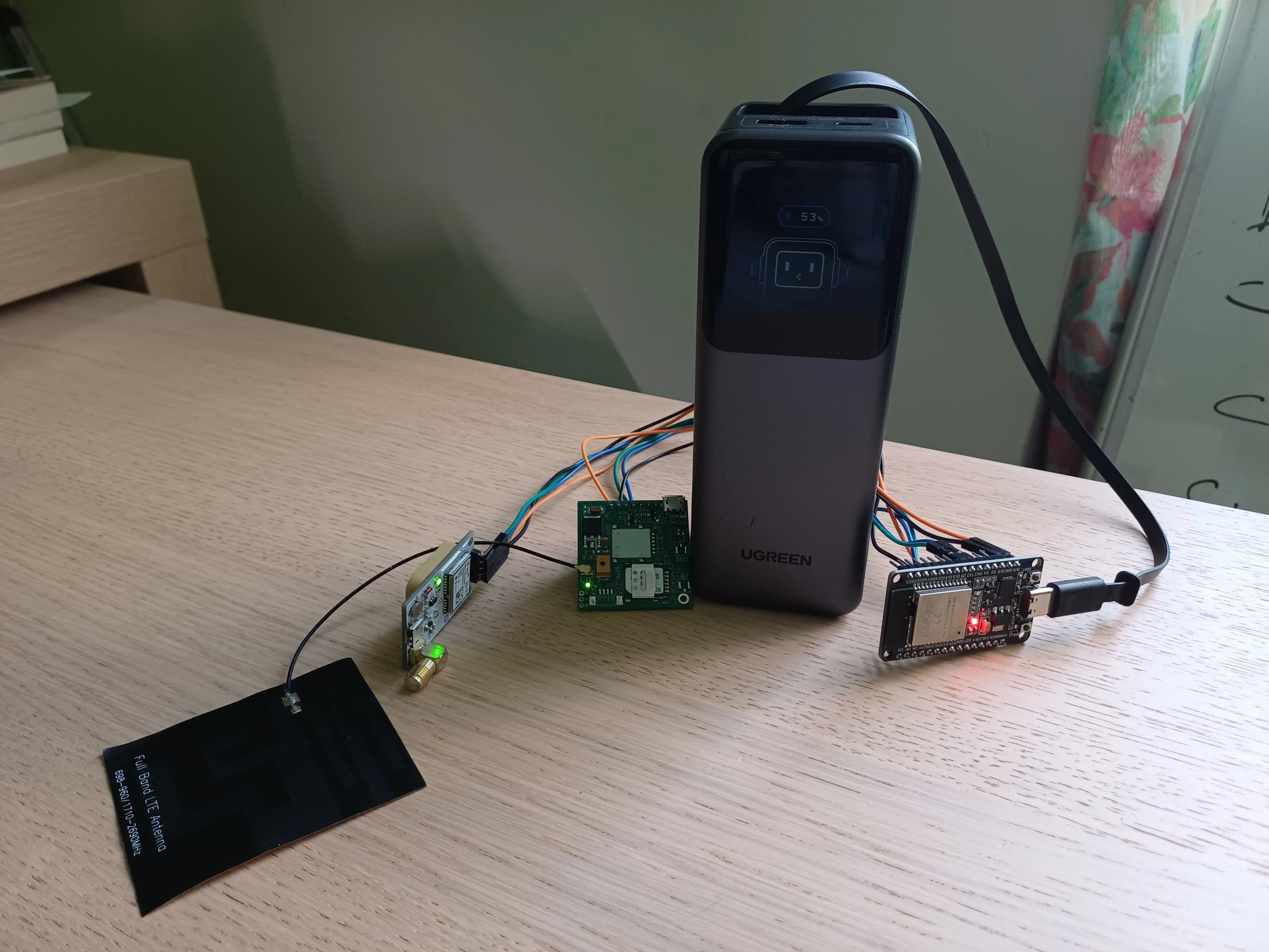 Le prototype du tracker GPS : modules électroniques, antenne et batterie reliés sur une table.